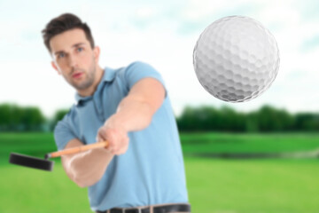 Young man playing golf on green course, focus on flying ball