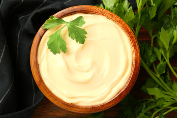 Delicious mayonnaise sauce with parsley in bowl on wooden table, top view