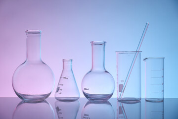 Laboratory glassware on mirror surface against color background