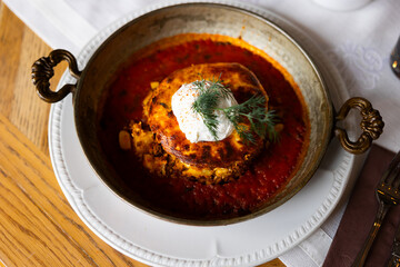 Appetizing Bulgarian moussaka with lamb and beef cooked with tomato sauce, potatoes, eggplant, bechamel and fetaki sauce in a round plate view from above. Delicious Bulgarian dish on a table with