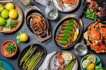 Shrimp and seafood delicacies served in pans with vibrant garnishes and fresh ingredients displayed on a dining table with wine