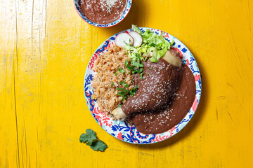 Delicious mole poblano chicken with rice on yellow background