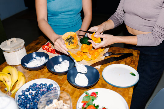 Direct-flash close-up of two unknown ladys preparing healthy snaks