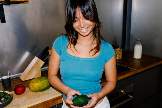Chinese woman with a joyful expresion holding an avocado