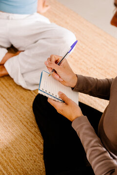 Unidentified woman jotting down handwritten notes in a journal