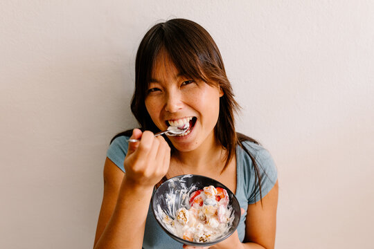 Portrait of Chinese lady enjoying a spoonful of healthy bowl of fruit