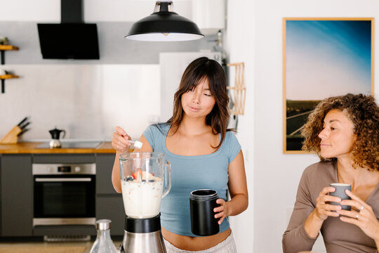 Multiracial friends prepare a fruit smoothie with protein supplement