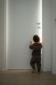 A toddler walks around at home and tries to open a door