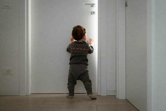 A toddler walks around at home and tries to open a door
