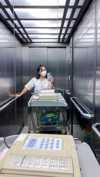 Medical worker in elevator with equipment cart