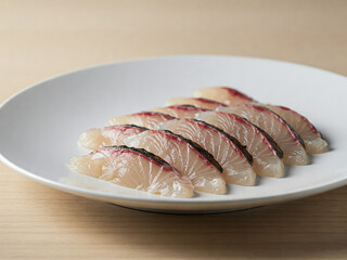 A plate of Hirame Sashimi on a wooden table.