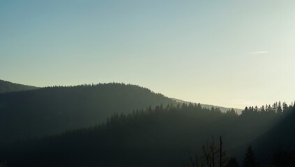 Fototapeta premium Serene mountainous landscape at dawn with misty forests and soft sunlight