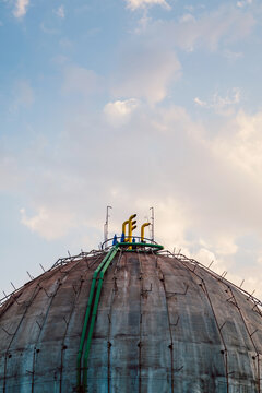 Large concrete dome of a gasometer with colorful pipes
