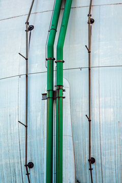 Green pipes running along a large industrial tank