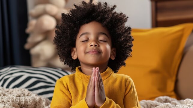 A young child is praying in a yellow shirt