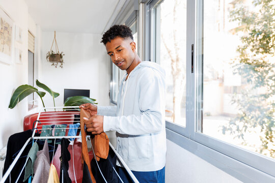 Young man at home hanging laundry