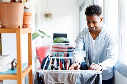 Young man at home hanging laundry