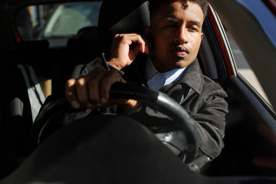 young driver in the car in sunlight in the city