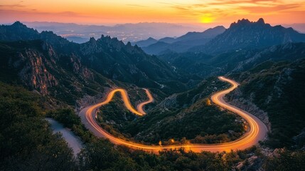 Winding mountain road at sunset, light trails, distant city