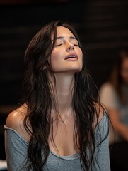 Fototapeta premium Meditative woman with eyes closed in grey top and long hair