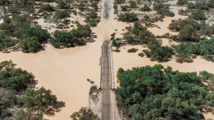 Drone shot the bridge above Eyre Creek at the entrance of  Bedourie, Diamantina Shire, channel country, Queensland, during March 2025 floods