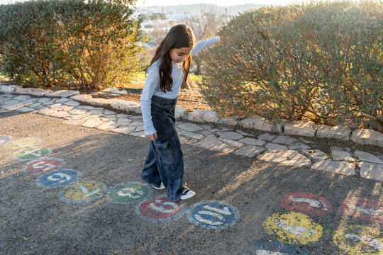Young Girl Plays Hopscotch on a Sunny Afternoon Outdoors