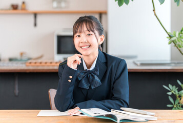 家で勉強する制服姿の小学生,中学生,高校生の女の子
