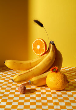 Bananas, orange and lemon on checkered tablecloth. Natural still life
