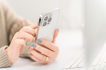 スマホ・スマートフォンの画面をタッチするネイルをした女性
