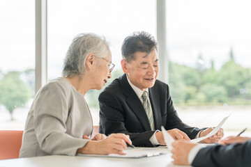 提案された書類を確認する高齢者夫婦（資産運用・相談・投資・遺産）

