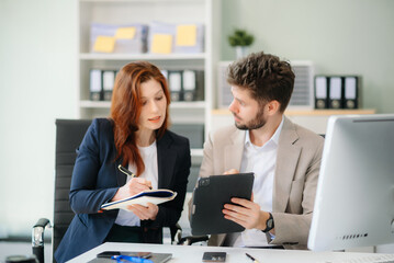 Two business workers talking on the smartphone and using laptop at office.