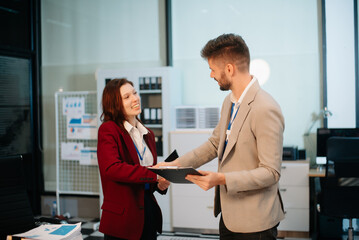 Two business professionals shaking hands in an office, symbolizing partnership, success, and teamwork.