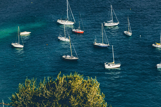 Yachts, sailboats, boats floating on calm blue water.