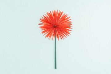 A vibrant red flower with spiky petals on a green stem against a soft blue background, showcasing a bold and playful design.