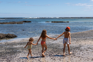 Children's walking on the beach hand in hand.