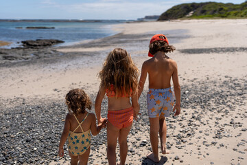 Children's walking on the beach hand in hand.