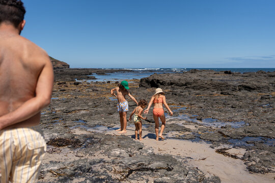 Children's exploring rock pools looking for crabs. - Powered by Adobe