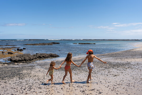 Children's walking on the beach hand in hand. - Powered by Adobe