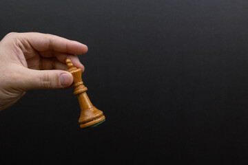 Hand holding a chess king against a black background