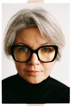 Mature woman with gray hair wearing large black glasses
