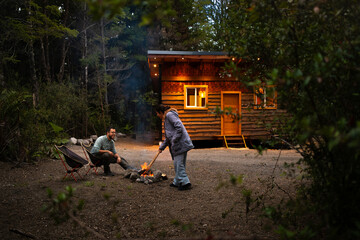 romantic Couple by a Campfire in Front of a Rustic Cabin in the Woods
