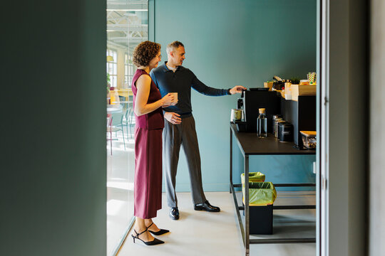 Businesspeople preparing coffee in office break room