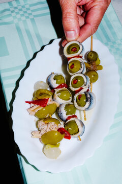 man takes a spanish banderilla, a skewer with pickles