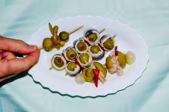 man taking a spanish banderilla, a skewer with pickles
