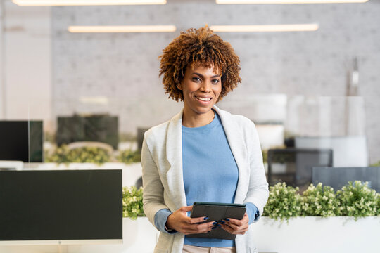 Smiling businesswoman holding digital tablet in modern office