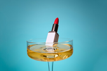 Red Lipstick Submerged in Champagne Glass Against Blue Background