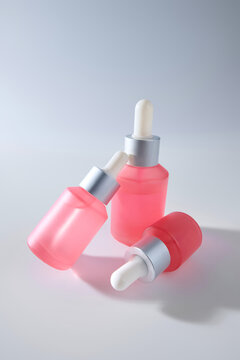 Three Pink Glass Dropper Bottles with Silver Caps. wide frame