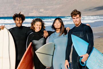 Medium shot portrait of mixed group of surfer friends posing together