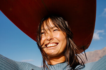 Close-up portrait of surfer balancing a surfboard on her head