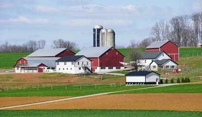 Obraz premium A picturesque farm scene unfolds, showcasing various barns and silos against a backdrop of rolling hills and vibrant green fields near Lancaster County, Pennsylvania, U.S.A